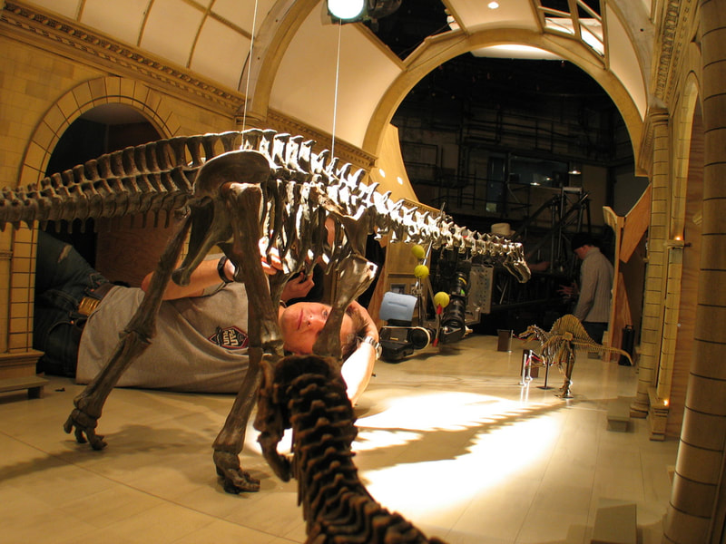 Artist adjusting scale model of a dinosaur.