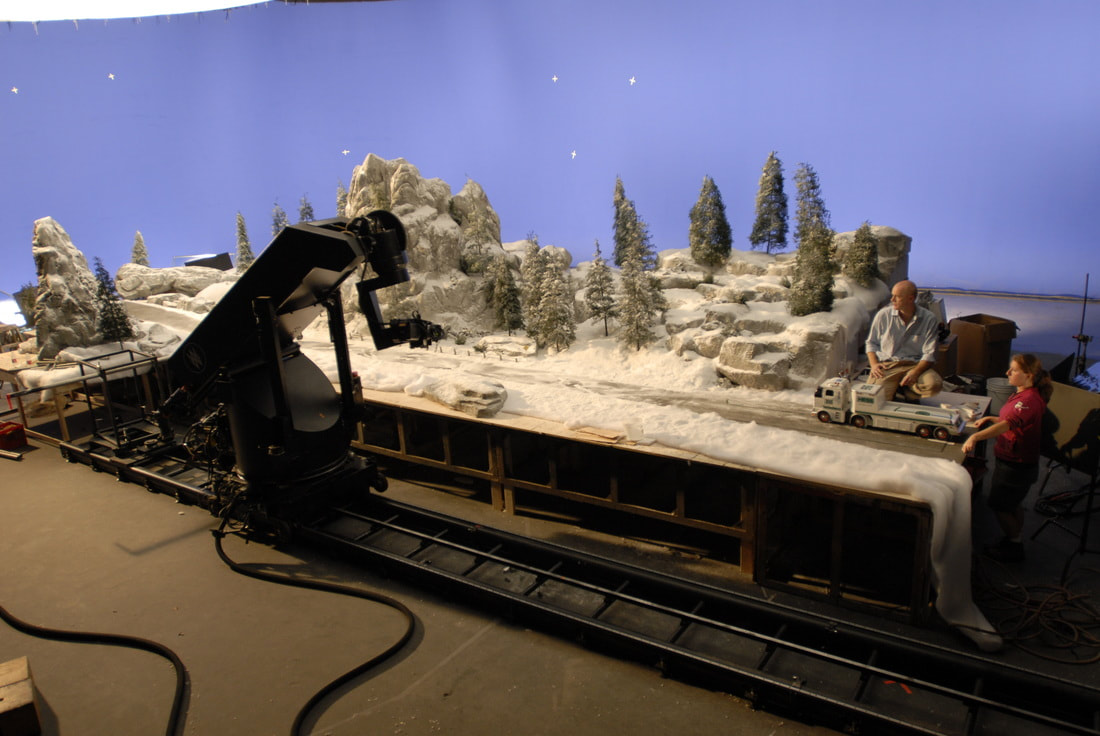 Miniature scale model of a snowy road with pine trees and a semi truck.